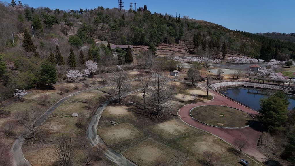 オートサイト（電源なし）の空撮。春の区画、桜、池まわりの様子