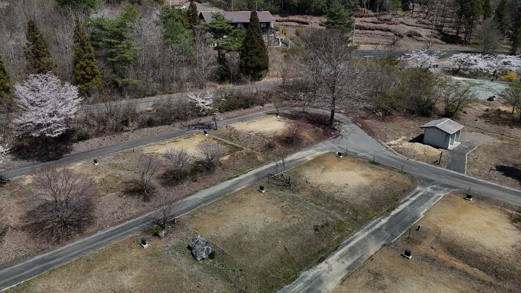 オートサイト（電源あり）の空撮。区画・電源設備と春の樹木